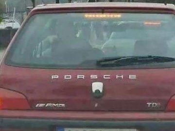 Une Peugeot 106 rouge équipée du sigle Porsche.