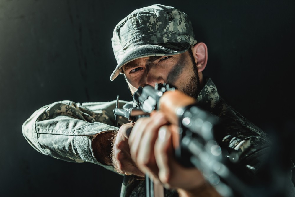 Un homme vêtu d'une tenue militaire, avec un fusil.