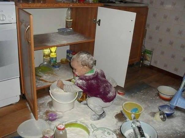 Un enfant se roule dans la farine dans la cuisine
