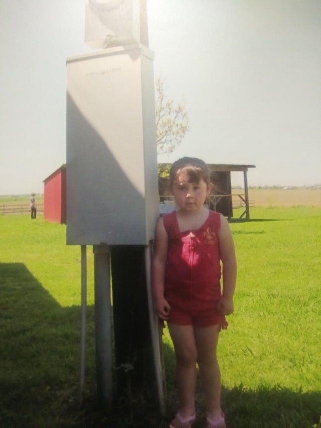 Une petite fille qui pose devant un compteur électrique.