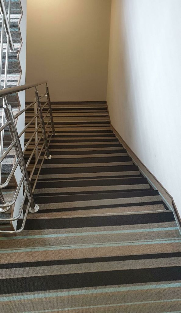 Des marches d'escalier recouvertes d'une moquette.