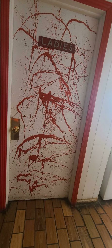 Une porte de toilettes aspergée de peinture rouge.