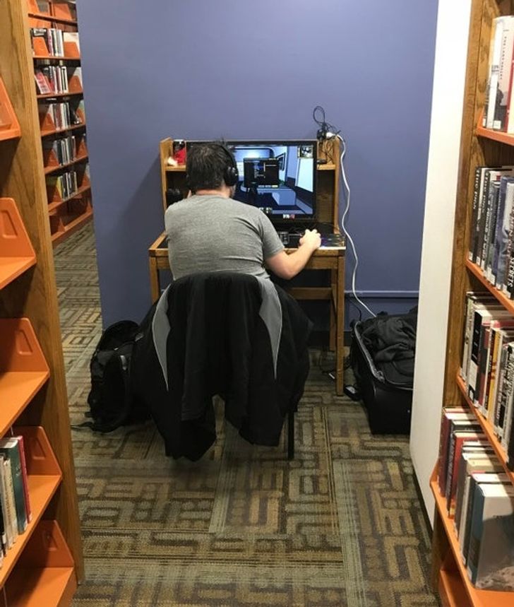 Un gamer avec son ordinateur dans une bibliothèque